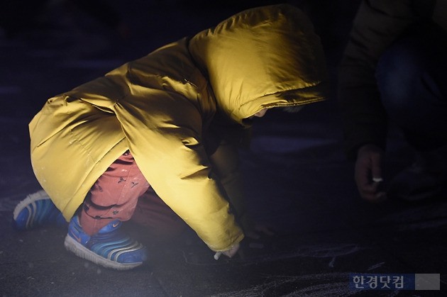 박근혜 정부 퇴진을 요구하는 '4차 촛불집회'가 19일 오후 서울 광화문 광장에서 열렸다, 어린 아이가 바닥에 촛불을 그리고 있다. / 변성현 한경닷컴 기자 byun84@hankyung.com
