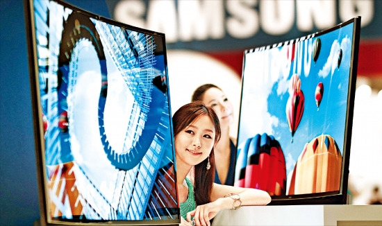 21일 서울 삼성동 코엑스에서 개막한 ‘월드 IT쇼 2013’에서 삼성전자 모델들이 55인치 ‘곡면 OLED TV’를 소개하고 있다. 연합뉴스