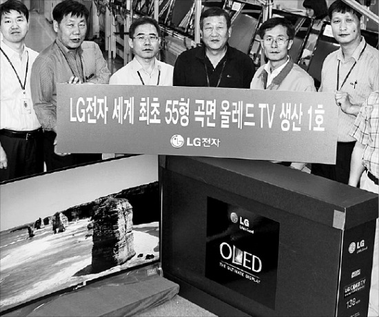 LG전자의 구미 TV공장 직원들이 화면이 오목하게 휘어진 곡면 OLED TV 1호 생산제품을 놓고 기념촬영하고 있다.  /LG전자 제공.
 