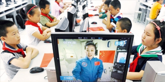 중국 안후이성 허베이시의 한 초등학교 학생들이 20일 오전 여성 우주인 왕야핑이 실험용 우주정거장 톈궁(天宮) 1호에서 진행한 물리학 강의를 CCTV 중계를 통해 보고 있다. 베이징신화연합뉴스