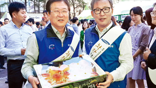 전동수 삼성전자 사장(오른쪽)은 지난 4일 열린 서초 농산물 직거래장터에서 박상진 삼성SDI 사장(왼쪽)에게서 복숭아 20박스를 산 뒤 자신이 팔던 포도도 20박스를 판매했다. 김현석 기자