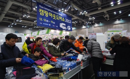경기도 고양 킨텍스 2전시장(7A홀)에서 열리고 있는 캠핑아웃도어쇼를 찾은 관람객들이 마운틴이큅먼트가 내놓은 의류, 장갑, 모자 등 방한제품을 살펴보고 있다. / 사진. 이선우 기자 seonwoo_lee@hankyung.com 
