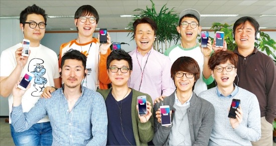 박수만 비트패킹컴퍼니 대표(뒷줄 가운데)와 직원들이 라디오 서비스 ‘비트’를 실행한 스마트폰을 들어 보이며 환하게 웃고 있다. 