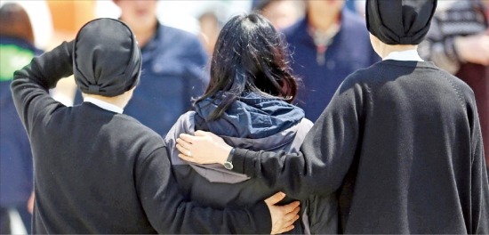 < 위로의 두손 > 여객선 세월호 침몰 6일째인 21일 전남 진도군 팽목항에서 천주교 수녀들이 실종자 가족을 위로하고 있다. 연합뉴스