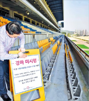 < 문 닫은 경마장 > 한국마사회 직원이 지난 20일 경기 과천시 렛츠런파크 서울에서 경마 경기의 취소를 알리는 표지판을 세우고 있다. 마사회는 25~27일 경마도 취소했다. 정동헌 기자 dhchung@hankyung.com