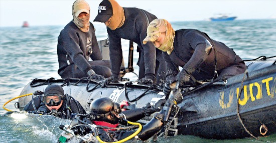 세월호 실종자 수색 작업에 투입된 잠수사들이 지난 22일 저녁 동료의 도움을 받아 보트에 오르고 있다. 해군 제공
