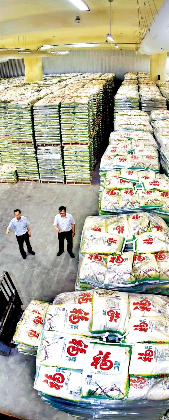 < 창고 꽉 채운 수입쌀 > aT 직원들이 경기 평택의 한 민간업체 창고에서 중국산 쌀 부대를 빼곡하게 쌓고 있다. 이 창고는 축구장 2개 넓이다. 평택=정동헌 기자 dhchung@hankyung.com
