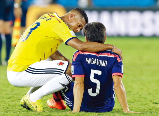 < “일어나!” > 일본 축구대표팀이 브라질 쿠아이바에서 25일(한국시간) 열린 콜롬비아와의 월드컵 C조 경기에서 1-4로 패해 16강 진출에 실패했다. 경기가 끝난 뒤 그라운드에 주저앉은 일본의 유토 나가토모(오른쪽)를 콜롬비아의 프레디 구아린(왼쪽)이 위로하고 있다. AP연합뉴스