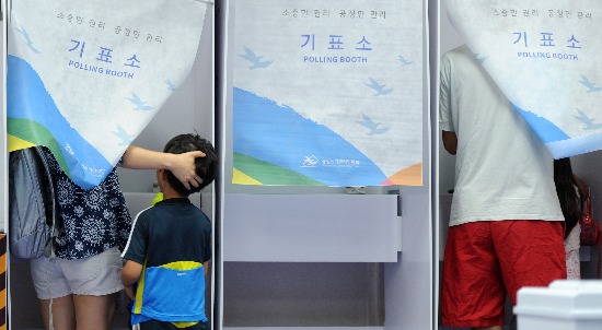 7·30 국회의원 재·보궐선거일인 30일 오전 경기도 수원시 팔달구 인계동 매여울초등학교에 마련된 수원병 보궐선거 인계동 제5투표소에서 어린이들이 부모님의 투표 과정을 지켜보고 있다. 연합뉴스