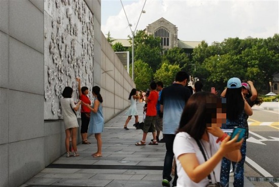 지난달 31일 이화여대 정문 벽의 배꽃 부조 앞에서 중국 관광객들이 기념사진을 찍고 있다.