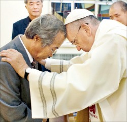 세월호 참사로 숨진 안산 단원고 학생 이승현 군의 아버지 이호진 씨(왼쪽)가 17일 서울 궁정동 주한 교황청대사관에서 프란치스코 교황에게 세례성사를 받고 있다. 천주교 교황방한위원회 제공