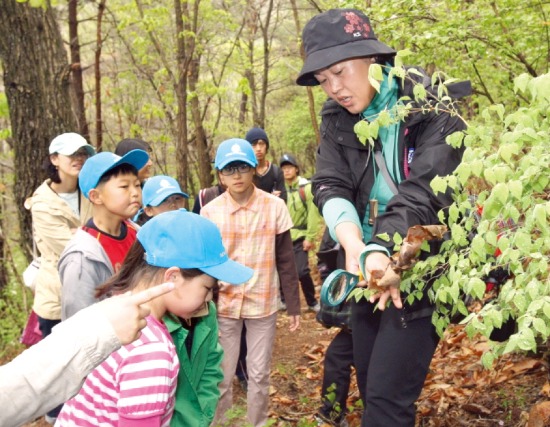 백운산에서 숲 해설가가 아이들에게 숲의 생태에 대해 설명하고 있다. 