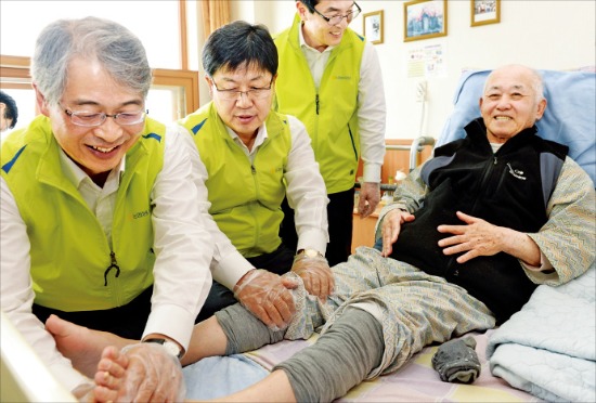 임종룡 농협금융지주 회장(왼쪽 첫 번째)이 지난 6월 ‘호국보훈의 달’을 맞아 수원보훈요양원을 방문해 한 국가유공자에게 발 마사지를 하고 있다. 농협금융  제공 