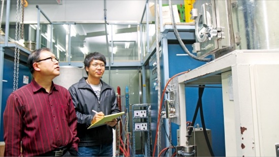 문병문 한국생산기술연구원 수석연구원(왼쪽)이 금속 가공 중에 발생하는 티타늄 스크랩에서 불순물을 걸러내 다시 순수한 티타늄 잉곳을 만드는 설비를 둘러보고 있다. 한국생산기술연구원 제공