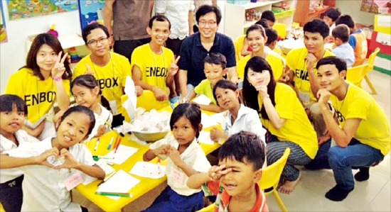 최용상 교수(가운데 검은색 옷)와 이화여대 학생들이 지난 7월 초 캄보디아 봉사활동에서 조이풀 유치원생들에게 ‘얼음과 소금, 주스로 아이스크림 만들기’ 수업을 하고 있다. 최용상 교수 제공