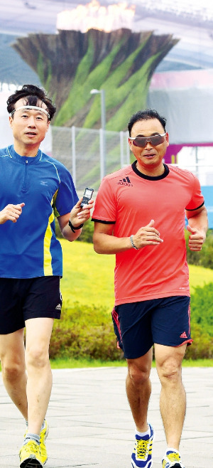 ‘국민마라토너’ 이봉주(오른쪽)가 정구학 부국장과 함께 성화가 타오르는 인천 아시안게임 주경기장 밖을 뛰고 있다. 정 부국장은 뛰는 내내 손에 녹음기를 들고 대화 내용을 담았다. 김병언 기자 misaeon@hankyung.com