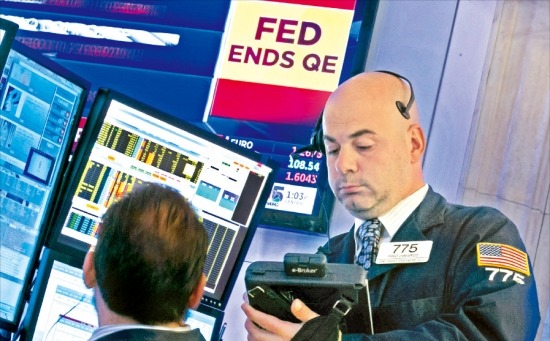 < ‘QE는 끝났다’ > 미국 중앙은행(Fed)이 29일(현지시간) 양적 완화 를 종료한다고 발표한 직후  뉴욕증권거래소(NYSE) 직원들이 시황을 살펴보고 있다. 뉴욕AP연합뉴스