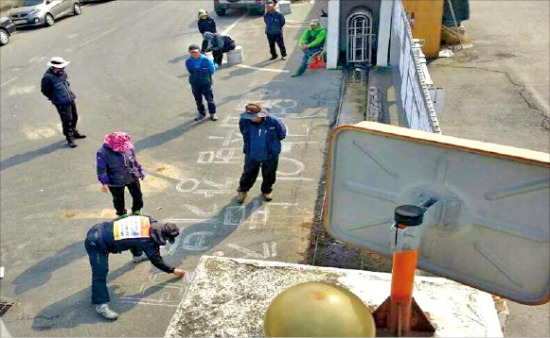 지난 9월 금속노조 해고노동자들이 경주 발레오전장시스템스코리아 본사 정문 앞 바닥에 낙서를 하고 있다. 발레오전장시스템스코리아제공