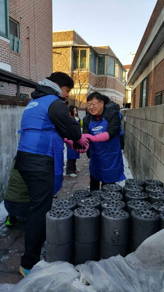 삼성전기 직원들이 서울의 한 쪽방촌에서 홀몸노인에게 전달할 연탄을 나르고 있다.  삼성전기 제공