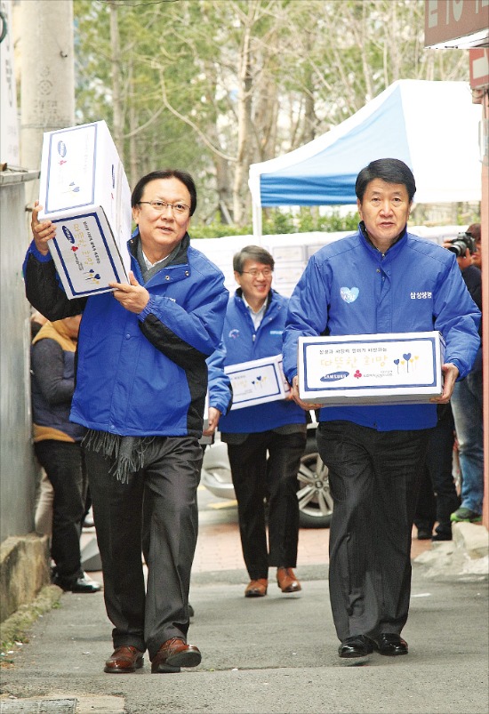 박근희 삼성사회봉사단 부회장(왼쪽)과 김창수 삼성생명 사장이 지난 11일 서울 동자동에 있는 쪽방촌에서 홀몸노인에게 나눠줄 상자를 나르고 있다.  삼성 제공
 