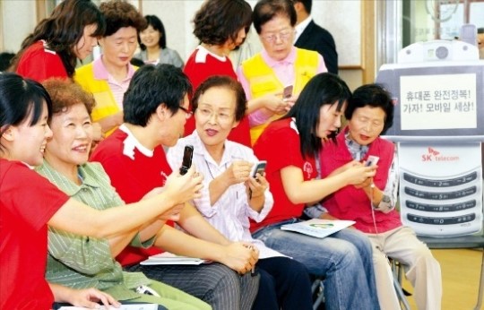 고령자에게 휴대폰은 여전히 높은 벽이다. 스마트폰 기능이 갈수록 복잡해지면서 디지털 세상에서 소외되는 고령층도 늘고 있다. SK텔레콤이 대학생 자원봉사자들과 함께 서울의 한 노인종합복지관에서 '어르신 휴대폰 교육' 행사를 하고 있다. SK텔레콤 제공 