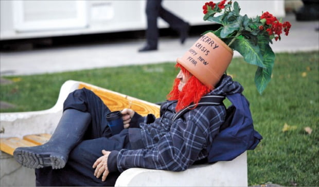 재정위기를 겪고 있는 그리스 아테네의 신타그마광장에서 한 노숙인이 ‘행복한 (재정)위기와 새로운 공포를 맞이하세요(merry crisis and happy new fear)’라는 문구가 쓰인 화분 모양 모자를 쓰고 앉아 있다. 