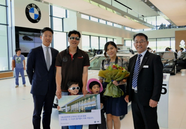 장성택 BMW 드라이빙 센터장(오른쪽 첫번째)이 10만번째 내방고객 홍혜란 씨와 홍우기 씨 가족에게 축하 화환을 전달하고 기념 촬영을 하고 있는 모습. (사진=BMW코리아 제공)