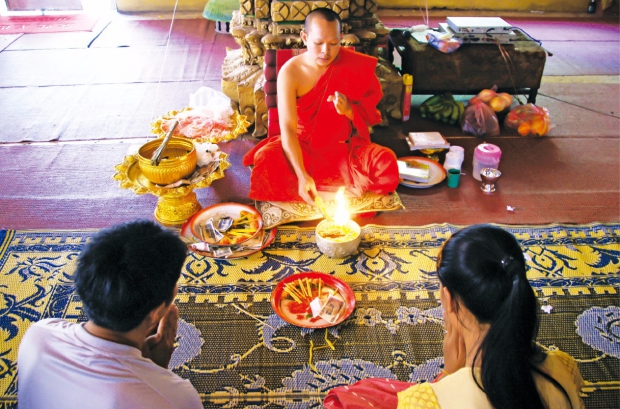 왓 시무앙 사원에서 스님이 신도들에게 라오스의 전통 축북 기원 의식인 ‘맏켄’을 하고 있다. 