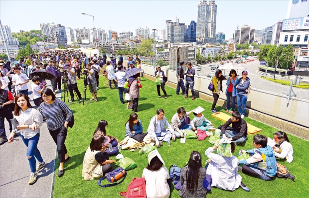 < 서울역고가 개방…피크닉 즐기는 시민들 > 서울역 고가도로 시민 개방행사가 열린 10일 오후 고가에 임시 설치된 인조잔디밭에서 시민들이 피크닉을 즐기고 있다. 허문찬 기자 sweat@hankyung.com