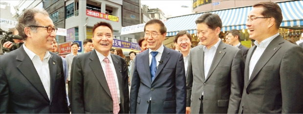 신세계백화점과 서울시, 중소기업청은 24일 서울 중구 메사빌딩에서 남대문시장을 ‘글로벌 명품 시장’으로 육성하는 내용의 업무협약을 맺었다. 한정화 중소기업청장(왼쪽부터), 김재용 남대문시장상인회장, 박원순 서울시장, 최창식 중구청장, 장재영 신세계백화점 대표가 협약식 후 시장을 둘러보며 대화하고 있다. 연합뉴스