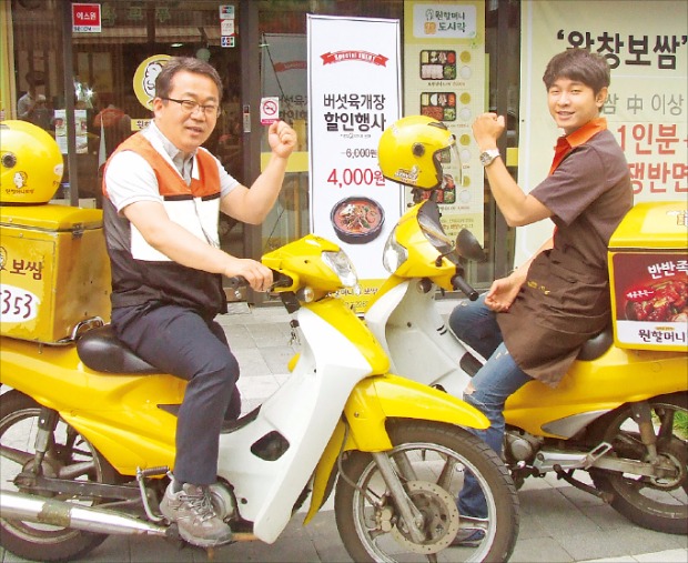 ‘원할머니보쌈·족발’ 가맹점주인 김용담 사장(왼쪽)이 직원과 함께 배달 나갈 채비를 하고 있다. 원앤원 제공 