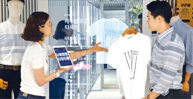코오롱FnC의 스마트 스토어 1호점인 ‘시리즈’ 코엑스점에서 30일 소비자가 옷에 대한 설명을 듣고 있다. 코오롱은 대형 스크린과 CCTV, 센서, 태블릿PC 등 정보기술(IT) 장치를 활용한 새로운 판매기법을 시도하고 있다. 김병언 기자 misaeon@hankyung.com