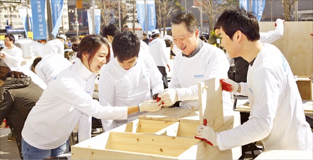 박용만 회장을 비롯한 두산 임직원 200여명이 지난 3월23일 ‘두산인 봉사의 날’ 행사를 맞아 서울 중구 두산타워 광장에서 저소득층 가정에 전달할 ‘따뜻한 가구 만들기’ 작업을 하고 있다. 