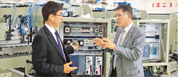 이철 에이스기계 사장(오른쪽)이 시화MTV 공장에서 정해일 반월시화기업성장지원센터장과 포장박스 자동접착기의 성능 향상 방안을 논의하고 있다. 