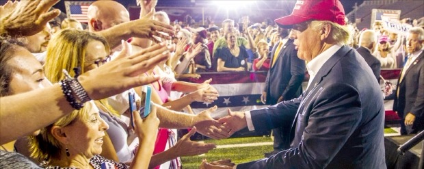< “불법 이민자 추방” > 도널드 트럼프 미국 공화당 대선 경선 후보가 21일 미국 앨라배마주 모빌에서 지지자들의 손을 잡고 있다. 모빌AFP연합뉴스