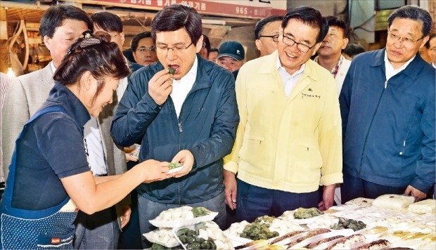 < 경동시장서 떡 맛보는 황 총리 >  황교안 국무총리가 24일 추석을 앞두고 서울 경동시장을 찾아 상인들을 격려하던 중 한 상인이 건네준 떡을 맛보고 있다. 허문찬 기자 sweat@hankyung.com