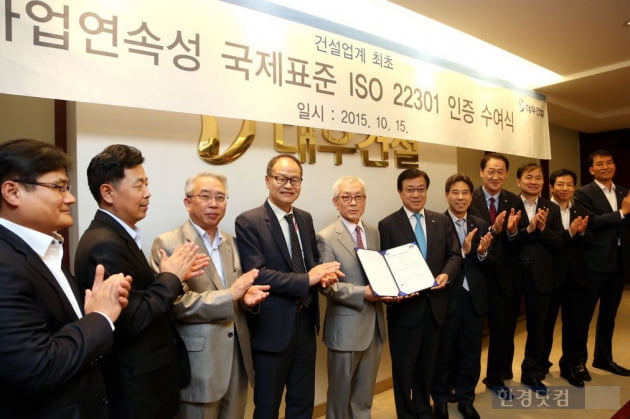 대우건설 지홍근 HSE-Q실장(오른쪽)과 BSI Korea 천정기 회장이 ISO 22301 인증패를 들고 관계자들과 함께 기념촬영을 하고 있다. (자료 대우건설)