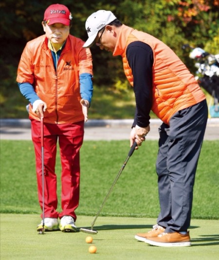 오르막 퍼팅은 홀컵 뒷벽을 맞고 들어가는 강한 이미지를, 내리막 퍼팅은 눈물방울이 똑 떨어지는 듯한 부드러운 이미지를 그린 뒤 퍼팅하면 효과가 좋다는 게 문경안 회장(왼쪽)의 조언이다. 이관우 기자가 문 회장이 알려준 ‘공 대 공’ 퍼팅 연습을 해보고 있다. 신경훈 기자 nicerpeter@hankyung.com