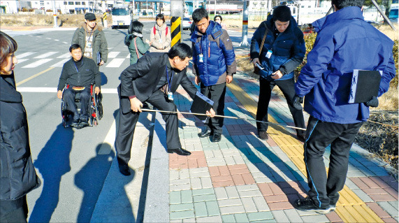 진주시 관계자들이 휠체어 통행이 가능하도록 보도블록을 낮추고 있다. 진주시청 제공