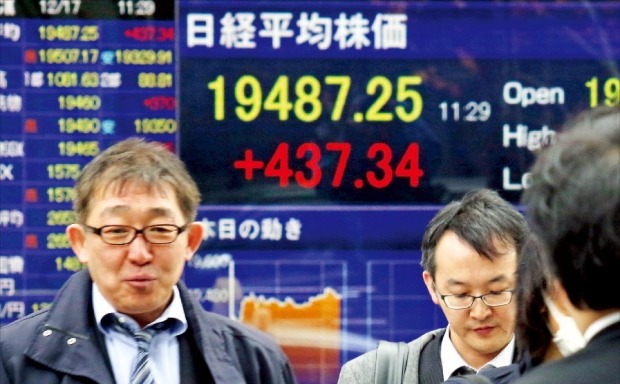 세계 증시가 일제히 오른 17일 오전 일본 도쿄 시민들이 니혼바시의 도쿄증권거래소 전광판 앞을 지나고 있다. 이날 닛케이225 지수는 미국 금리 인상에 따른 불확실성 해소에 힘입어 전날보다 1.59% 오른 19,353.56으로 마감했다. 도쿄AFP연합뉴스