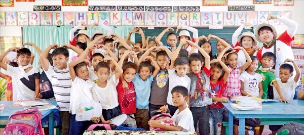 지난 15일 비씨카드 빨간밥차 해외봉사단원들이 필리핀 타클로반 말라기까초등학교에서 학생들과 기념촬영하고 있다. 비씨카드 제공 