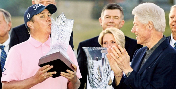 < 클린턴도 축하 박수 > 제이슨 더프너(왼쪽)가 25일 PGA투어 커리어빌더챌린지에서 우승한 뒤 빌 클린턴 전 미국 대통령(오른쪽)에게 넘겨받은 트로피에 입을 맞추고 있다. AP연합뉴스
