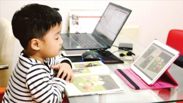 웅진북클럽 회원인 한 어린이가 태블릿PC를 통해 디지털 전집책을 보고 있다. 웅진씽크빅 제공