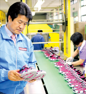 문창섭 삼덕통상 회장이 생산라인에서 신발을 점검하고 있다.