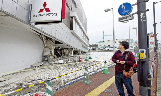 한 행인이 18일 일본 남서부 규슈 구마모토현을 강타한 지진으로 무너진 미쓰비시자동차 건물을 바라보고 있다. 구마모토EPA연합뉴스