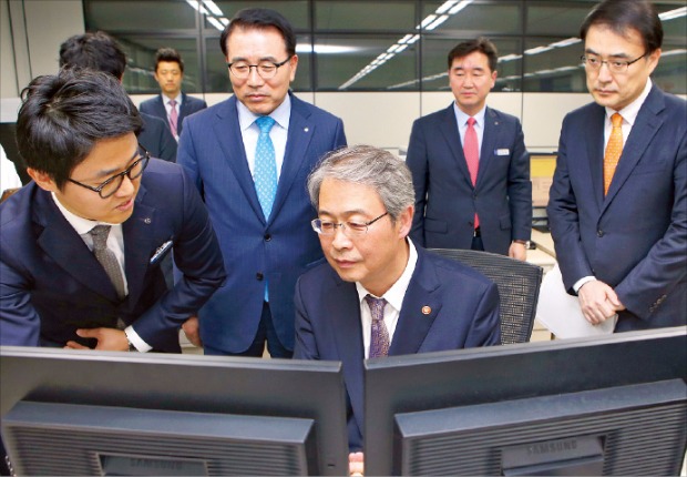 임종룡 금융위원장(가운데)이 지난달 21일 서울 세종대로 신한은행 본점을 방문해 ‘2015년 하반기 기술금융 실적평가’에서 시중은행 1위를 차지한 신한은행(행장 조용병·뒷줄 왼쪽)의 기술금융 지원 시스템에 대한 설명을 듣고 있다. 