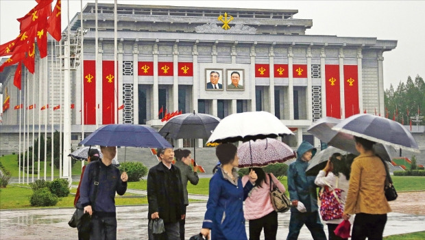 북한 노동당 제7차 대회가 6일 평양 4·25문화회관에서 개막했다. 노동당기가 걸린 4·25문화회관 앞을 북한 주민들이 우산을 쓰고 지나가고 있다. 북한은 외신기자들의 접근을 차단한 채 이날 행사를 비공개로 치렀다. 평양AP연합뉴스