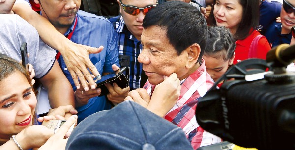 < 얼굴 꼬집혀도 좋아! > 필리핀 대통령선거에서 당선이 확실시되는 로드리고 두테르테 후보가 9일 다바오시의 다니엘아기날도 국립고등학교에서 투표를 마친 뒤 떠나자 한 지지자가 그의 볼을 꼬집고 있다. 다바오AP연합뉴스
