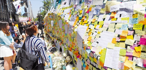 시민들이 20일 서울 강남역 10번 출구 외벽에 지난 17일 발생한 '강남 묻지마 살인사건'의 희생자 추모 메시지를 적은 포스트잇을 붙이고 있다. 연합뉴스 