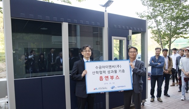 오경록 수공아이엔씨 대표(사진 오른쪽)가 김광 산학협력단장에게 흡연부스를 전달하고 있다. 사진 뒤가 흡연부스. 산기대 제공